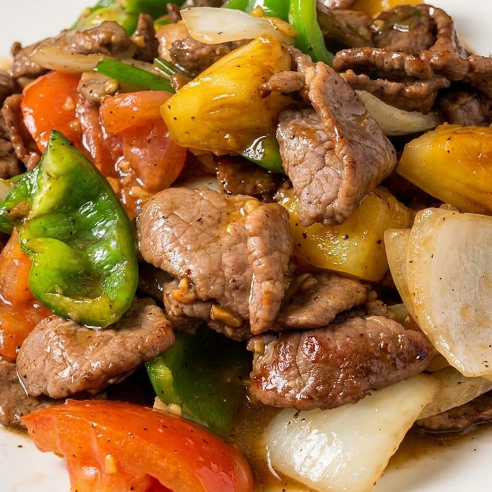 Sautéed beef with green peppers, tomatoes, onions, and yellow squash served on a white plate.
